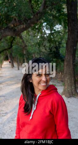 portrait de la jeune femme regardant l'appareil photo et souriant dans un parc verdoyant au coucher du soleil Banque D'Images