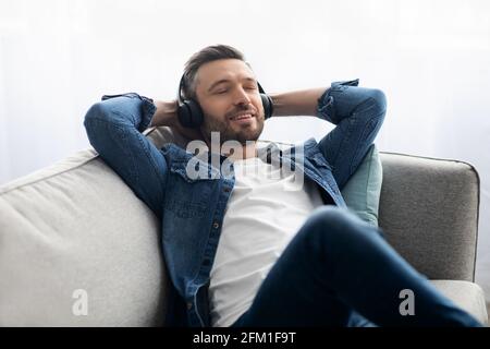 Joyeux homme d'âge moyen dans un casque à l'écoute de la musique Banque D'Images