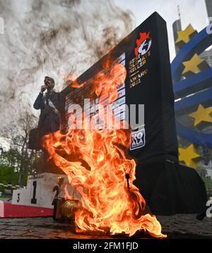 Hessen, Francfort-sur-le-main, le 05 mai 2021 : lors de la présentation du « Best Climate Killer Award 2021 » par le groupe activiste « KoalaKollektiv » à la Deutsche Bundesbank, devant la sculpture de l'euro dans le quartier bancaire de Francfort, le trophée est en flammes. Par leur action, ils protestent contre l'attitude de blocus de la Bundesbank allemande concernant des mesures efficaces de protection du climat. Ils accusent la banque centrale allemande de bloquer la politique de la BCE sur la mise en œuvre de l'Accord de Paris sur le climat. Photo: Arne Dedert/dpa Banque D'Images