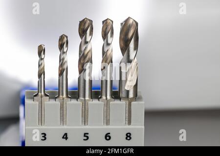 Jeu de forets en acier de tailles diverses avec queue hexagonale dans un support en plastique. Gros plan des outils de coupe pour la réalisation de trous. Lumière blanche sur un arrière-plan. Banque D'Images