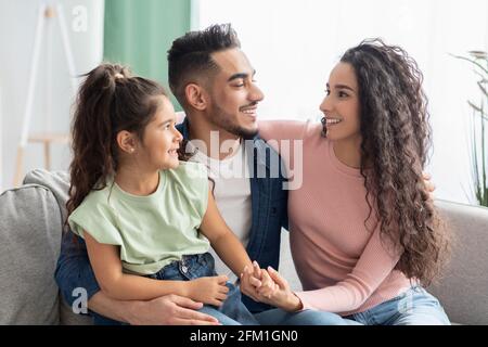 La famille d'abord. Bonne maman arabe, papa et fille s'embrassant sur le canapé Banque D'Images