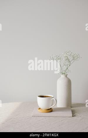 Décoration intérieure de style scandinave et nordique. Tasse de café et vase de fleur sur toile sur table. Mur blanc sur fond. Matin, bre Banque D'Images