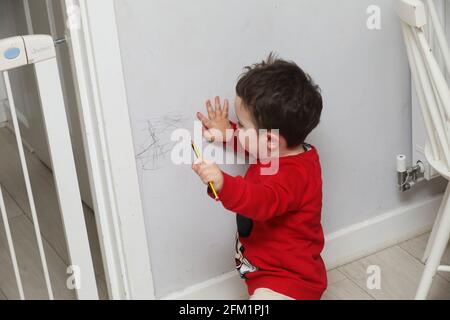 Un jeune garçon photographié en dessinant sur les murs avec un crayon à West Sussex, au Royaume-Uni. Banque D'Images