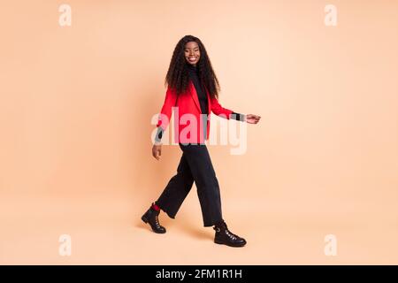 Photo de profil pleine grandeur de la jeune femme afro-américaine allez espace vide week-end isolé sur fond beige couleur Banque D'Images