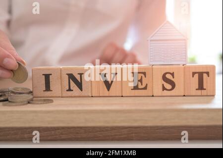 Investissement immobilier et hypothèque de maison concept financier, Word INVESTIR sur des cubes de bois et maison miniature sur table en bois. Concept d'investissement. Banque D'Images