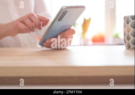 Gros plan des mains de la femme tenant le téléphone cellulaire pendant la pause café. Femme utilisant un smartphone. Banque D'Images