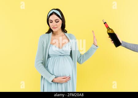 jeune femme enceinte refusant le vin rouge isolé sur jaune Banque D'Images