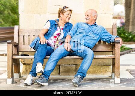 Couple senior heureux s'amuser sur un banc - concept De personnes âgées actives et joueuses à la retraite - mode de vie quotidien après-midi ensoleillé en automne Banque D'Images