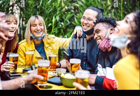 Les jeunes boivent de la bière avec masque ouvert - Nouveau concept de style de vie normal avec des amis milléniaux s'amusant ensemble l'happy hour à la brasserie Banque D'Images