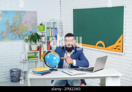 Meilleure éducation possible ici. Un élève de sexe masculin s'assoit dans une salle de classe avec carte. Examen réussi. Apprentissage du sujet. Géographe. Homme heureux avec barbe regarder Banque D'Images