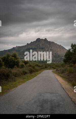 Route étroite par jour nuageux avec vue sur le paysage d'une colline de montagne de Monsanto, au Portugal Banque D'Images