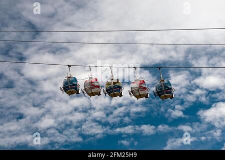 Alpe d'Huez cable cars in motion avec un ciel nuageux et fond de ciel bleu, région de l'Oisans, Isère (38), Alpes, France Banque D'Images