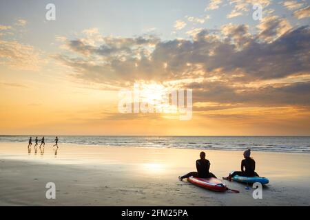 Paddleboarders assis sur leurs planches à regarder le lever du soleil, Sunny Sands, Folkestone, Kent, Angleterre Banque D'Images