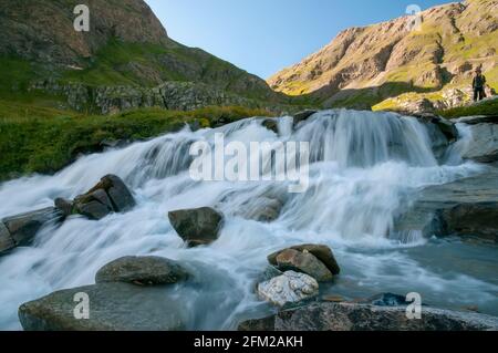 Photo d'un randonneur mâle debout près d'une cascade, près de Bonneval-sur-Arc, Alpes, Savoie (73), région Auvergne-Rhône-Alpes, France. Banque D'Images