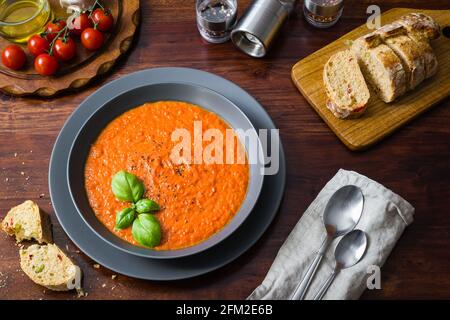 Soupe crémeuse de tomates garnie de basilic frais au milieu de tomates mûres Et des tranches de pain Ciabatta croustillant Banque D'Images
