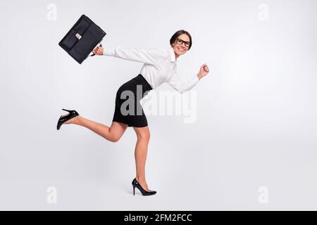 Pleine photo de profil de la brunette optimiste cheveux dame courir portez des lunettes jupe-chemise isolée sur fond gris Banque D'Images