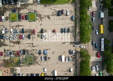 Vue aérienne en haut de la rue animée avec circulation de voitures en mouvement et grand parking avec beaucoup de véhicules garés. Banque D'Images