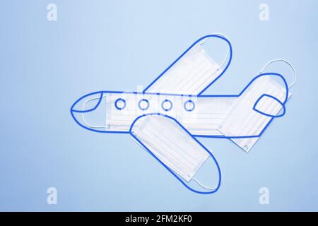 Modèle d'avion composé de masques de protection avec contour sur fond bleu. Concept de transport en avion sécurisé. Nouveau concept normal. Banque D'Images