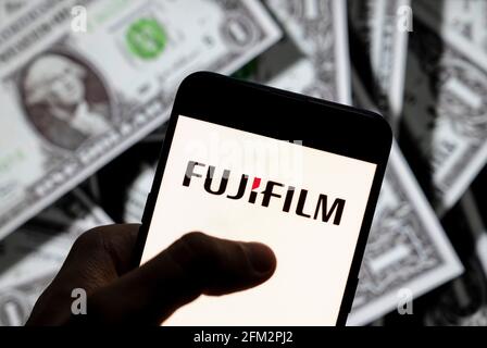 Sur cette photo, le logo de la société japonaise de photographie et d'imagerie Fujifilm est affiché sur un smartphone avec une devise en dollars américains (USD) en arrière-plan. Banque D'Images