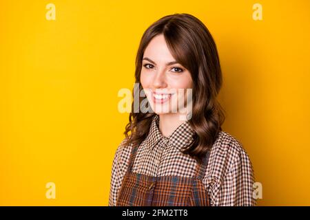 Photo de la moitié tournée jeune fille Toothy sourire regarder caméra portez des vêtements à carreaux isolés sur fond jaune Banque D'Images