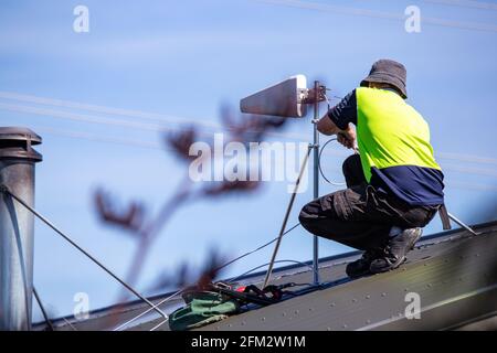 Un technicien en Internet mobile rural installe un yagi sur un toit pour se connecter au réseau cellulaire, ce qui donne aux résidents une connexion Internet, Canterbury. Banque D'Images