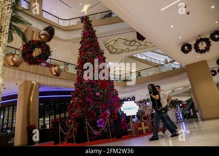 Les personnes portant des masques de protection contre la propagation de COVID-19 passent par des décorations de Noël dans un centre commercial de Taguig City, Metro Manila. Philippines. Banque D'Images
