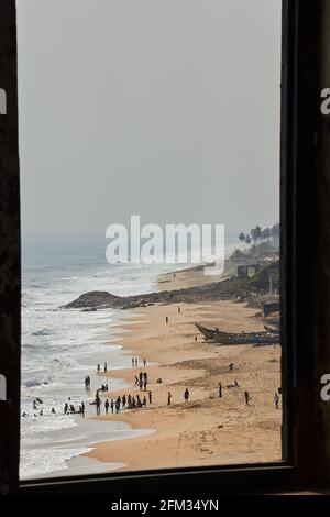 Vue par une fenêtre dans le château de Cape Coast du peuple ghanéen se détendant sur la plage de Cape Coast, Ghana Banque D'Images