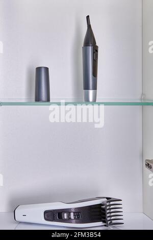 Les appareils ménagers pour les coupes de cheveux à la maison, tels que le nez, les sourcils et la tondeuse à oreilles et la tondeuse à cheveux à tête, sont rangés dans l'armoire murale de la salle de bains. Banque D'Images