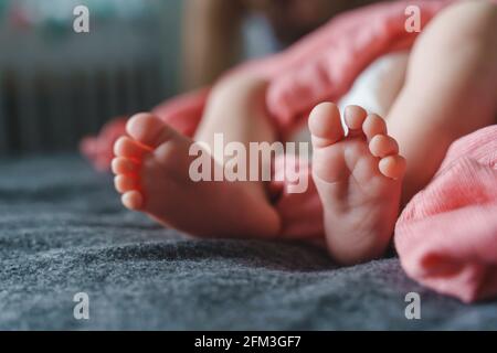 Gros plan sur les pieds d'un bébé inconnu allongé sur le concept lit nouveau-né Banque D'Images