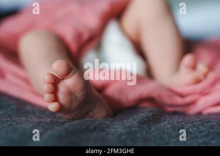 Gros plan sur les pieds d'un bébé inconnu allongé sur le concept lit nouveau-né Banque D'Images