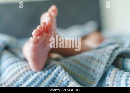 Gros plan sur les pieds d'un bébé inconnu allongé sur le concept lit nouveau-né Banque D'Images