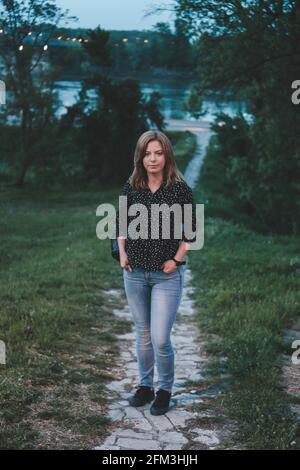 Tir vertical d'une jeune femme blonde caucasienne debout chemin dans un pa Banque D'Images