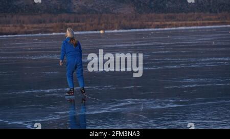 La jeune fille s'entraîne sur le patinage de vitesse sur glace. L'enfant skate en hiver dans un costume bleu de sport, des lunettes de sport. Sports de patinage de vitesse pour enfants. Banque D'Images