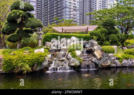 Cascade décorative et pierres entourant l'étang à poissons Koi en japonais jardin Banque D'Images