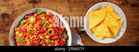 Panorama Chili con carne avec nachos, photo en hauteur sur fond de bois rustique foncé Banque D'Images