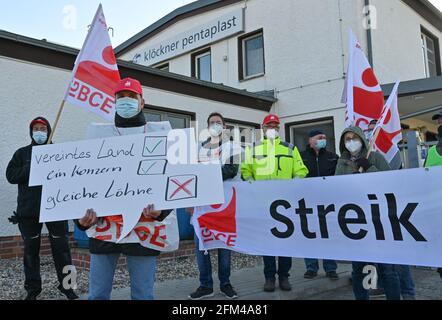 06 mai 2021, Brandebourg, Beeskow: Un employé du fabricant d'emballages Linpac tient un panneau indiquant "united Country, One group, EQUAL Wages" lors d'une grève d'avertissement devant les locaux de l'usine. Jeudi matin, les employés du fabricant d'emballages Linpac à Beeskow (district d'Oder-Spree) ont cessé de travailler. La grève d'avertissement de 24 heures a été déclenchée par l'Union industrielle des mines, de la chimie et de l'énergie (IG BCE). Avec l'action industrielle, le syndicat veut réaliser un contrat de maison propre pour l'entreprise. Les employés de Linpac à Beeskow gagnent beaucoup moins pour la même chose Banque D'Images