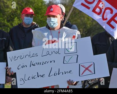 06 mai 2021, Brandebourg, Beeskow: Un employé du fabricant d'emballages Linpac tient un panneau indiquant "united Country, One group, EQUAL Wages" lors d'une grève d'avertissement devant les locaux de l'usine. Jeudi matin, les employés du fabricant d'emballages Linpac à Beeskow (district d'Oder-Spree) ont cessé de travailler. La grève d'avertissement de 24 heures a été déclenchée par l'Union industrielle des mines, de la chimie et de l'énergie (IG BCE). Avec l'action industrielle, le syndicat veut réaliser un contrat de maison propre pour l'entreprise. Les employés de Linpac à Beeskow gagnent beaucoup moins pour la même chose Banque D'Images