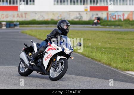 Ulyanovsk, Russie - 10 juin 2017. Un coureur moto en uniforme noir effectue une course d'entraînement sur une piste de sport Banque D'Images