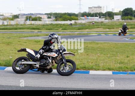 Ulyanovsk, Russie - 10 juin 2017. Un coureur moto en uniforme noir effectue une course d'entraînement sur une piste de sport Banque D'Images