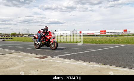 Ulyanovsk, Russie - 10 juin 2017. Un coureur moto en uniforme noir effectue une course d'entraînement sur une piste de sport Banque D'Images