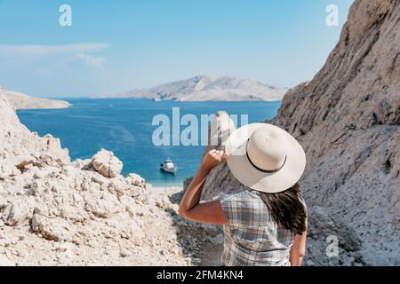 Vue arrière d'une femme sur un terrain rocheux avec vue spectaculaire sur la mer et le littoral en été. Banque D'Images