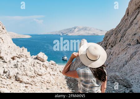 Vue arrière d'une femme sur un terrain rocheux avec vue spectaculaire sur la mer et le littoral en été. Banque D'Images