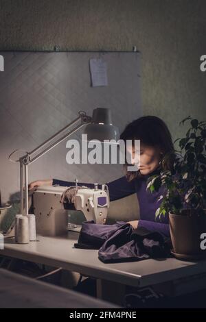 Femme couturière coudre des vêtements - veste tendance en velours sur une machine à coudre dans son studio. Banque D'Images