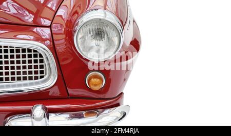 Vue avant d'une voiture vintage rouge brillante, isolée sur un fond blanc. Fait partie d'une voiture vintage rouge brillant avec phare et calandre, vue avant. Banque D'Images