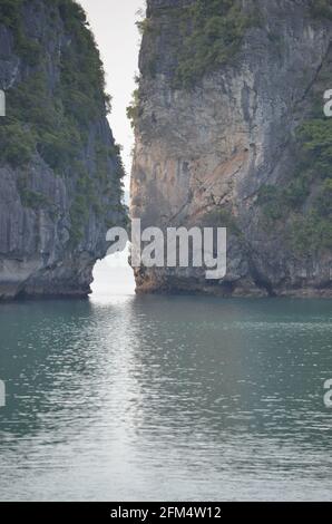 Vue panoramique du coucher de soleil sur les eaux étincelantes, les formations rocheuses, les montagnes bleues et les bateaux flottants sur la baie de Halong au Vietnam Banque D'Images