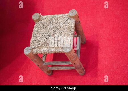 Tabouret avec siège en osier isolé sur fond rouge Banque D'Images