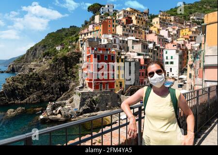 Riomaggiore, Cinque Terre, Ligurie, Italie. Juin 2020. Photo incroyable du village de bord de mer. Une femme d'âge moyen porte un masque pour se défendre contre le Th Banque D'Images