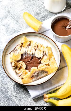 Crêpes, crêpes fines sur une assiette. Tartinade au chocolat et crêpes fourrées à la banane sur l'assiette. Crêpes savoureuses ou blini à la sauce sucrée. Banque D'Images