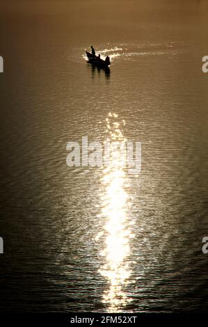 Un pirogue avec trois personnes à bord dans le reflet de la lumière du soleil couchant sur le Niger. 17.11.2003 - Christoph Keller Banque D'Images