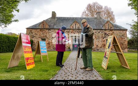 East Lothian, Écosse, Royaume-Uni, 6 mai 2021. Élections écossaises : l'un des bureaux de vote du comté alors que le peuple écossais va aux urnes. Photo : un couple âgé se prépare à voter à l'ancienne salle pittoresque du village de Tyninghame, qui est transformée en un lieu de vote avec des bureaux de vote des partis politiques électoraux locaux à l'extérieur Banque D'Images